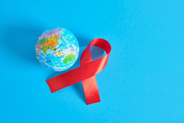World AIDS day. The symbol of solidarity is a red ribbon nd toy globe ball