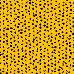 Abstract seamless pattern from small shapes. Simple background of irregular spots. Abstract wild animal skin print. Random spaced black spots. Vector illustration on amber background