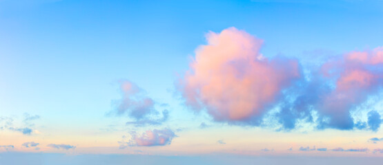 Light pink clouds in the blue sky during dawn sunset, real pastel colors. Panoramic background
