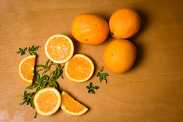 Naranjas enteras y en rodajas con hojas verdes sobre fondo cálido