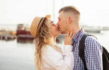 Young loving couple of tourists kiss on the background of the yacht club. Love, travel concept
