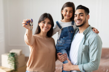 Happy family showing keys of their apartment, selective focus