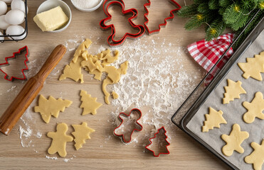 Making Christmas Cookies with traditional gingerbread cookies ingredients. Christmas Gingerbread man and fir trees on pan. Top view.