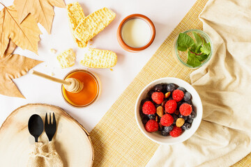 Autumn style breakfast with red fruits, nuts, honey, milk and toast