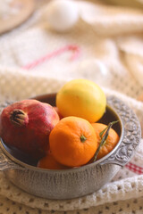 Silver bowl with various fruit, soft blanket and various Christmas decorations. Hygge at home. Selective focus.