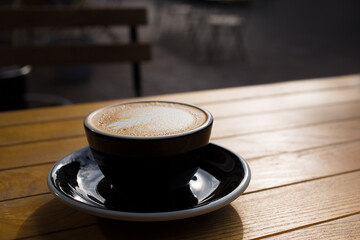 Cup of cappuccino with foam on a wooden table in a cafe.