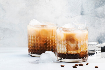 White russian cocktail, trendy alcoholic drink with vodka, coffee liqueur, cream and ice, gray background, bar tools