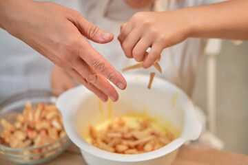 Mother and son cooking apple pie in the home kitchen. A woman and a boy in chef hats and aprons cook with pastries