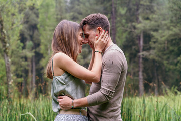 Side view of caucasian couple in love kissing and hugging. Horizontal view of couple kissing with love outdoors in nature background. People and travel concept.
