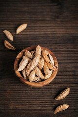 Pile of Almond nuts in a bowl on a dark wooden background