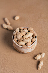 Pile of Peanuts in a bowl on a brown background
