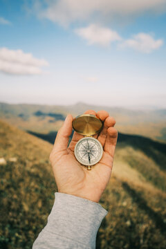 Vintage compass in a man's hand in the background a mountain landscape.