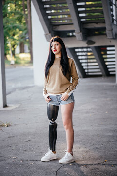 Beautiful girl with a prosthetic leg posing on the street.