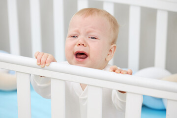 The little baby is crying in the crib, wants to sleep and milk teeth are climbing. Pediatric problems