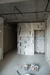 An empty room with a concrete ceiling, a foam wall and a concrete floor. There are electrical wires hanging from the ceiling. Room renovation concept.