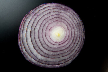 Sliced red onion rings, closeup top view of healthy food on black background, vegetable of rich vitamin, France