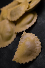 Tasty raw ravioli with flour and spinach on dark background, process of making italian ravioli, High quality photo