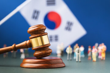 Judge gavel on blurred flag background and plastic toy men, concept of litigation in South Korea