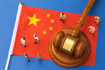 Judicial hammer, flag of China and plastic toy men on blue background, concept of litigation in...