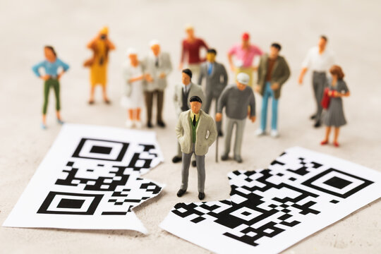 Plastic toy men and a sheet torn in half with a barcode, the concept of a rally of people against the introduction of the QR code system