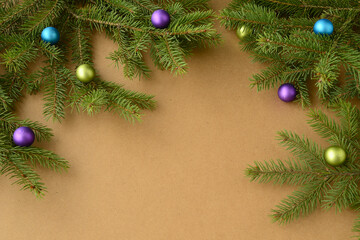Festive Christmas or New Year background with blue, purple and gold glass balls on fir branches. Christmas tree branches with colorful decorations on cardboard or eco-friendly kraft paper background