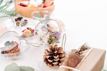 DIY ornaments with dried flowers and gift boxes on white background