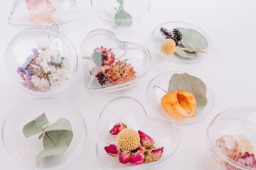 DIY ornaments filled with dried flowers on white background