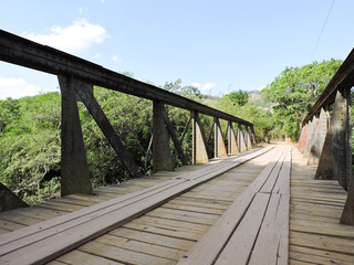 Fototapeta na wymiar Wooden bridge over the river in a clear sky day. Old bridge used by the railroad.