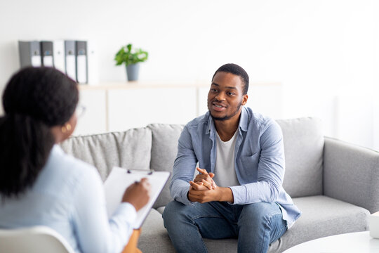 Effective psychotherapy. Young black guy talking to psychologist, receiving professional help at mental health clinic
