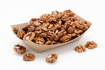 Walnuts in a craft box and a few nuts scattered around on a white background. Template for designers.