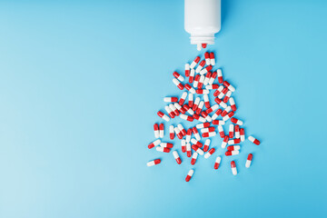 A scattering of white cans of Red and white ampoules with medicine and vitamins on a blue background.