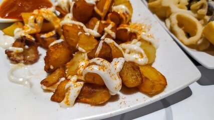 Typical Spanish tapas (patatas bravas) fried with various types of spicy sauce.