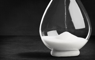 An hourglass with little time left sand on the desk.