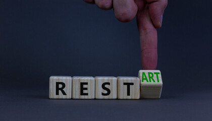 Rest and restart symbol. Businessman turns a wooden cube and changes the word rest to restart. Beautiful grey table, grey background, copy space. Business, rest and restart concept. - obrazy, fototapety, plakaty