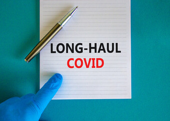 COVID-19 long-haul covid symptoms symbol. White card with words long-haul covid. Doctor hand, pen, beautiful blue background, copy space. Medical, COVID-19 long-haul covid symptoms concept.