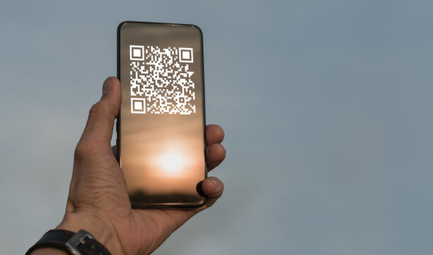 A man holds a smartphone with a QR code