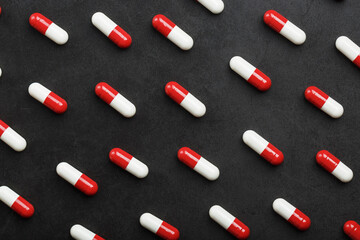 A pattern of red and white pills of medical pills on a black background