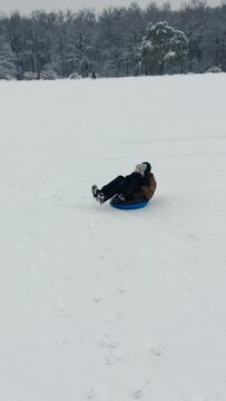 A small child with father rides a inflatable snow tube from a snowy mountain. Tubing in winter.