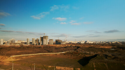 Fototapeta premium Construction site. Construction of modern multi-storey buildings. The work of construction cranes is visible. Against the background of the blue sky. Aerial photography.