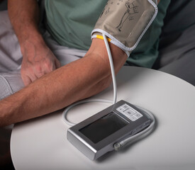 Blood pressure measuring and checking. Male hand on table with connected modern tool for cardio checkup at home.