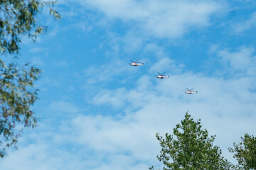 three helicopters are flying against the blue sky