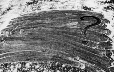 Fototapeta premium Black flour background. Close up of question mark on flour mixture