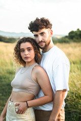 Lovely heterosexual couple in a grass field walking and kissing