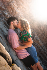 Heterosexual couple kissing in a rocky cove at the Basque Country.
