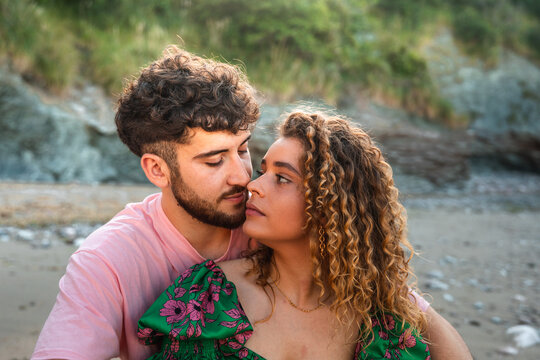 Heterosexual couple kissing in a rocky cove at the Basque Country.
