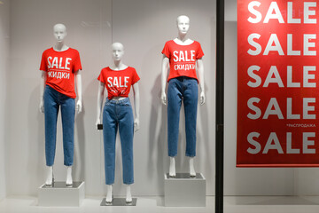 Mannequins in a shop window in red t-shirts with the inscription sale, black friday