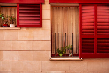Wooden vintage window with red shutters on a plastered stone wall in the Spanish style.