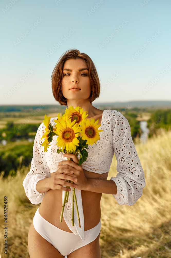 Wall mural Woman in lingerie poses with flowers in the field