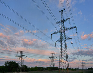 power line pylons during sunset with beautiful saturated sky. distribution transmission and...