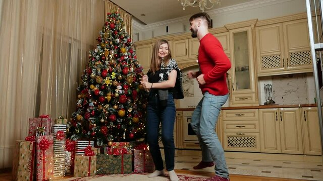 Couple dance near christmas tree in slowmotion in the kitchen. High quality FullHD footage